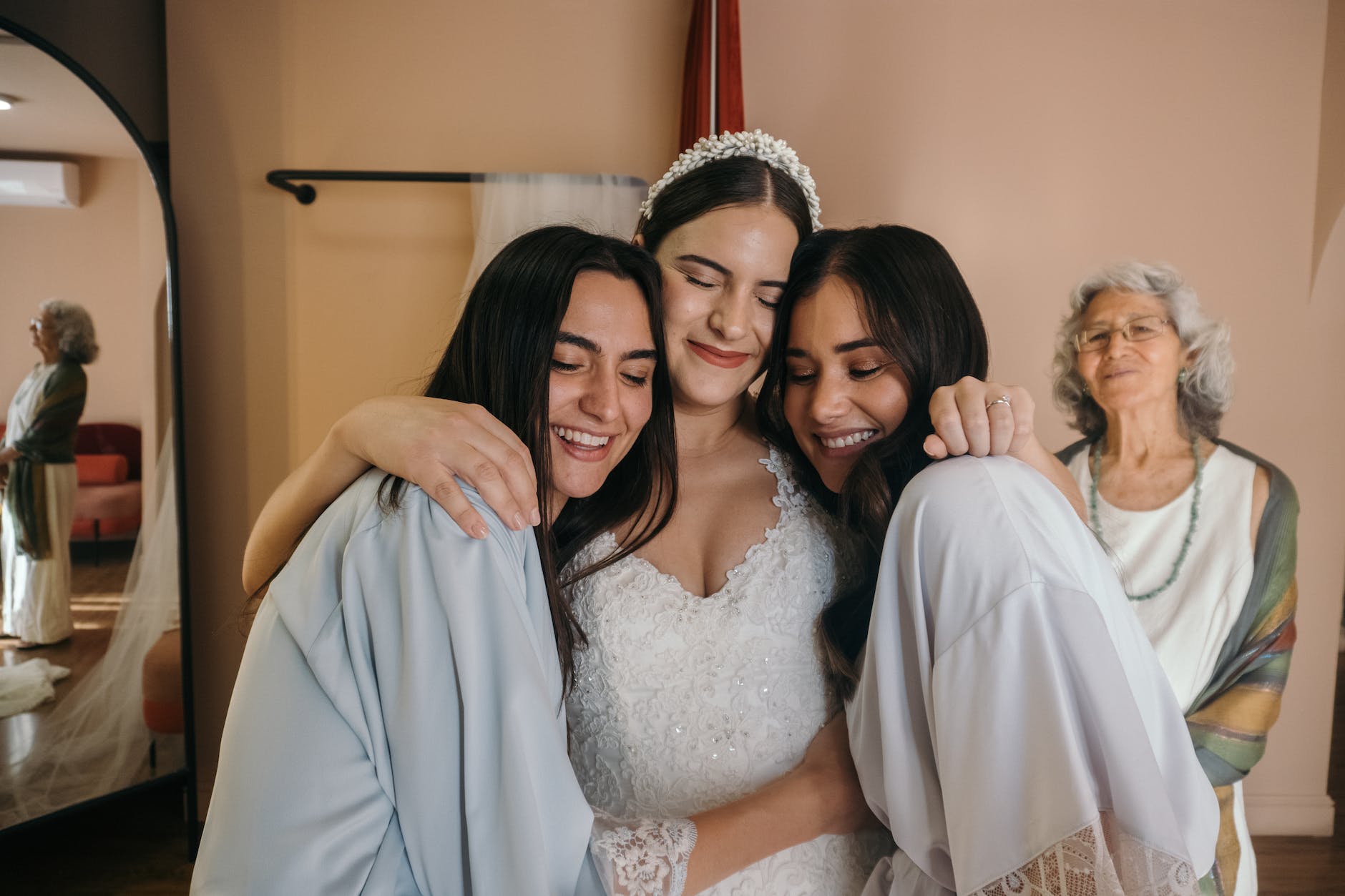 a woman in white wedding gown embracing her bridesmaids